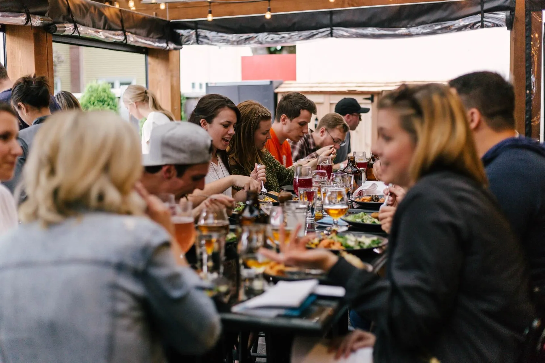 Diners sharing a meal around a long table in a busy restaurant