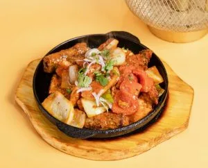 Curry with onions and peppers in a black iron pan