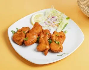 Golden fried pieces on a white plate with salad and lemon