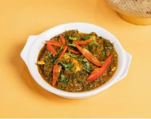 Green curry with strips of red pepper in a white dish